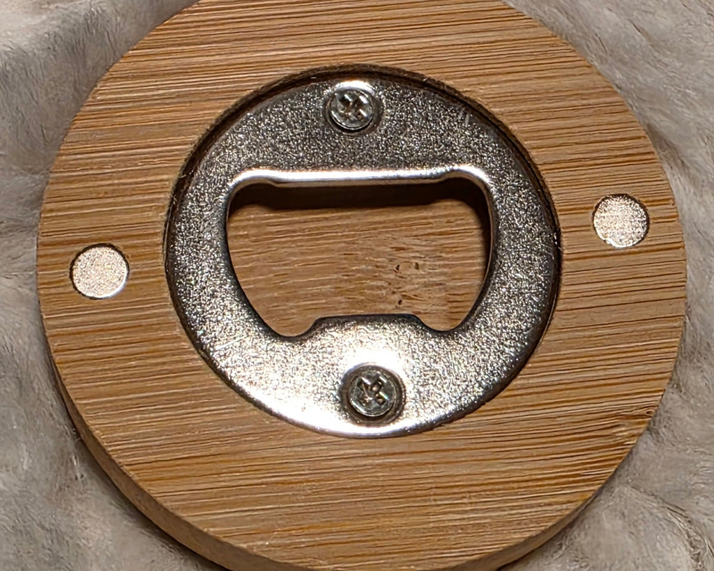 Bronze magnetic bottle opener with three duck-like characters and the word 'IMPOSTOR' on a textured surface
