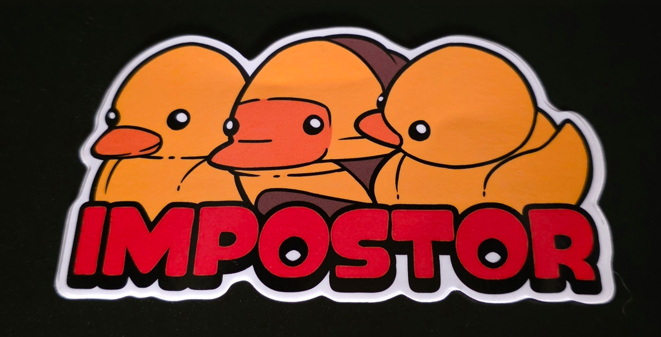 Sticker with three rubber ducks and the word 'Impostor' on a black background