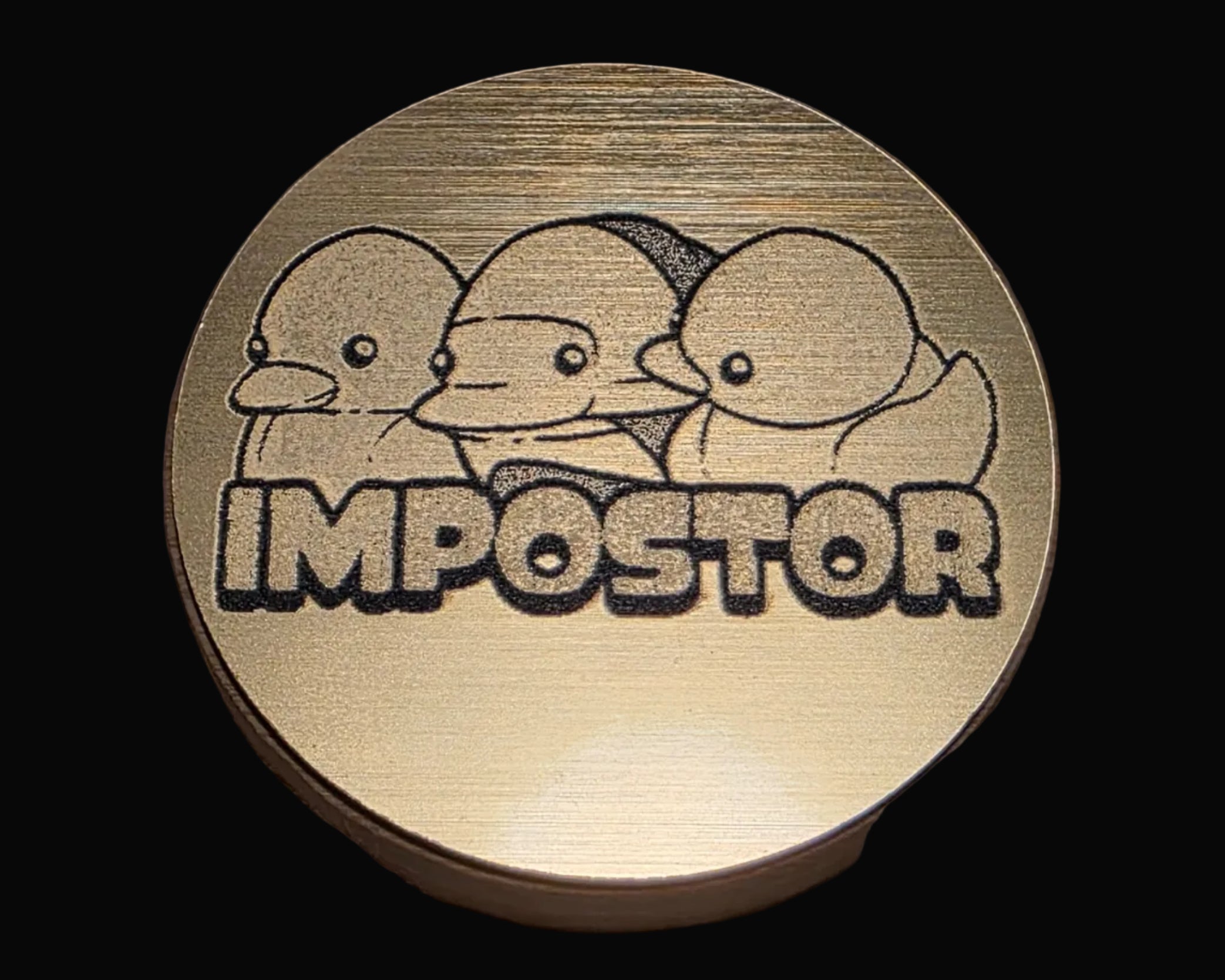 Bronze coin with three duck-like characters and the word 'IMPOSTOR' on a textured surface