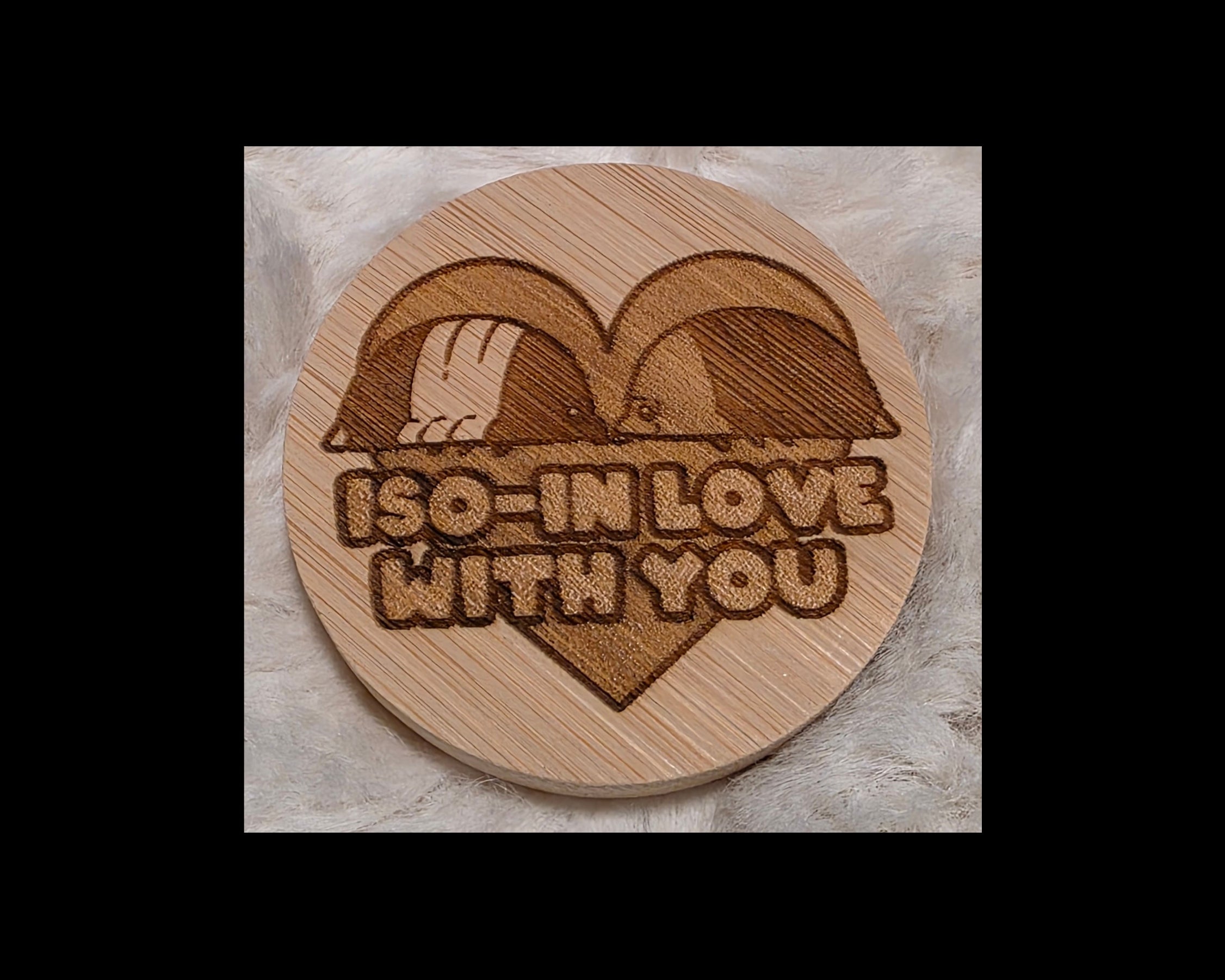 Wooden bottle opener with laser-cut design of two birds in a heart and 'I'm in love with you' text on a soft white background.