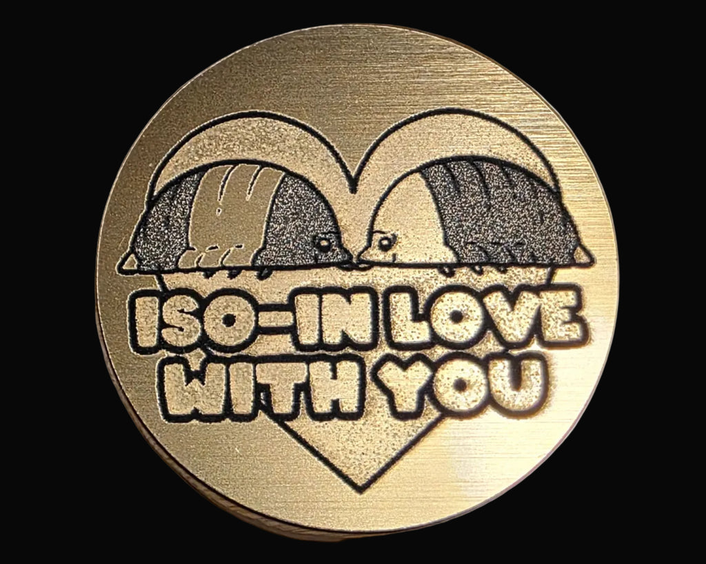 Bronze magnetic bottle opener with three duck-like characters and the word 'IMPOSTOR' on a textured surface