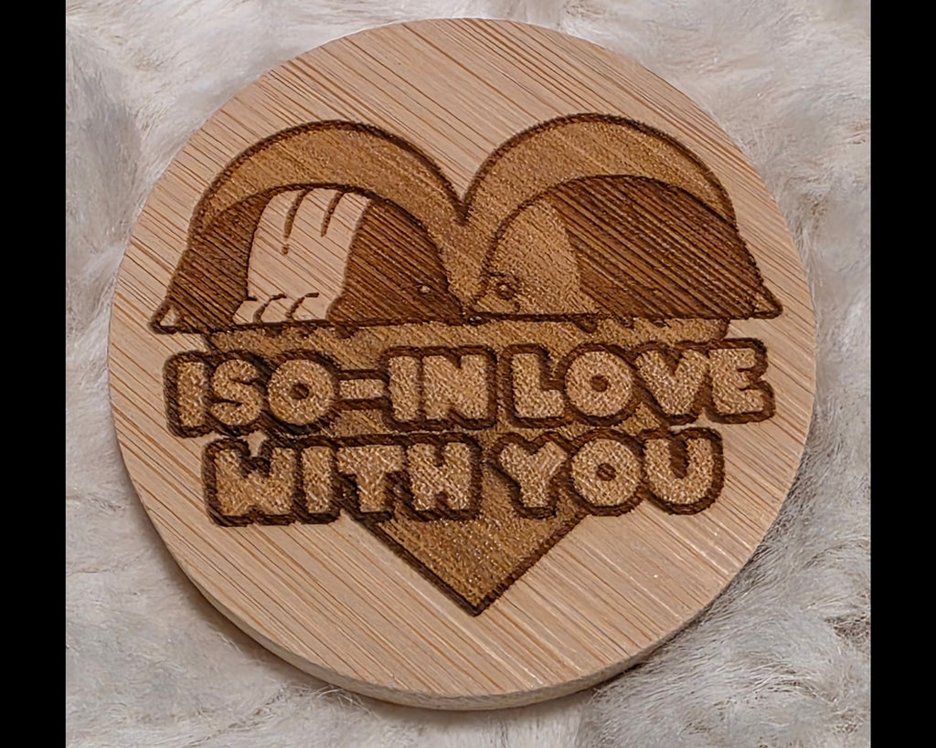 Wooden bottle opener with laser-cut design of two birds in a heart and 'I'm in love with you' text on a soft white background.